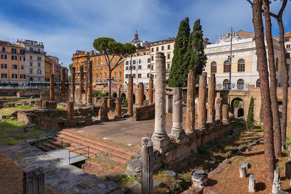 Largo di Torre Argentina square in city of Rome, Italy, ancient temple ruins (4 century BC – 1st century AD) and Teatro Argentina (1731) opera house and theatre in the background.